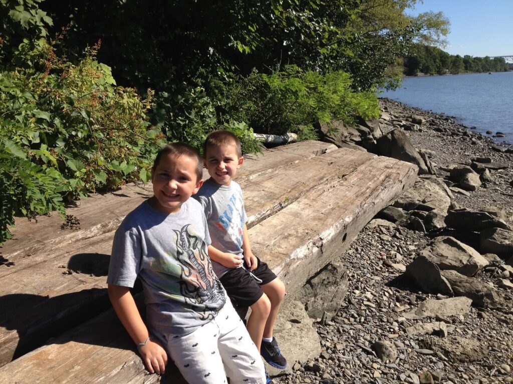 school age boys sitting on stone slab along the Hudson River, in summer