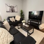 Black and white modern farmhouse apartment living room, with white throws and pillows, longhorn steer art, fiddle fern plant