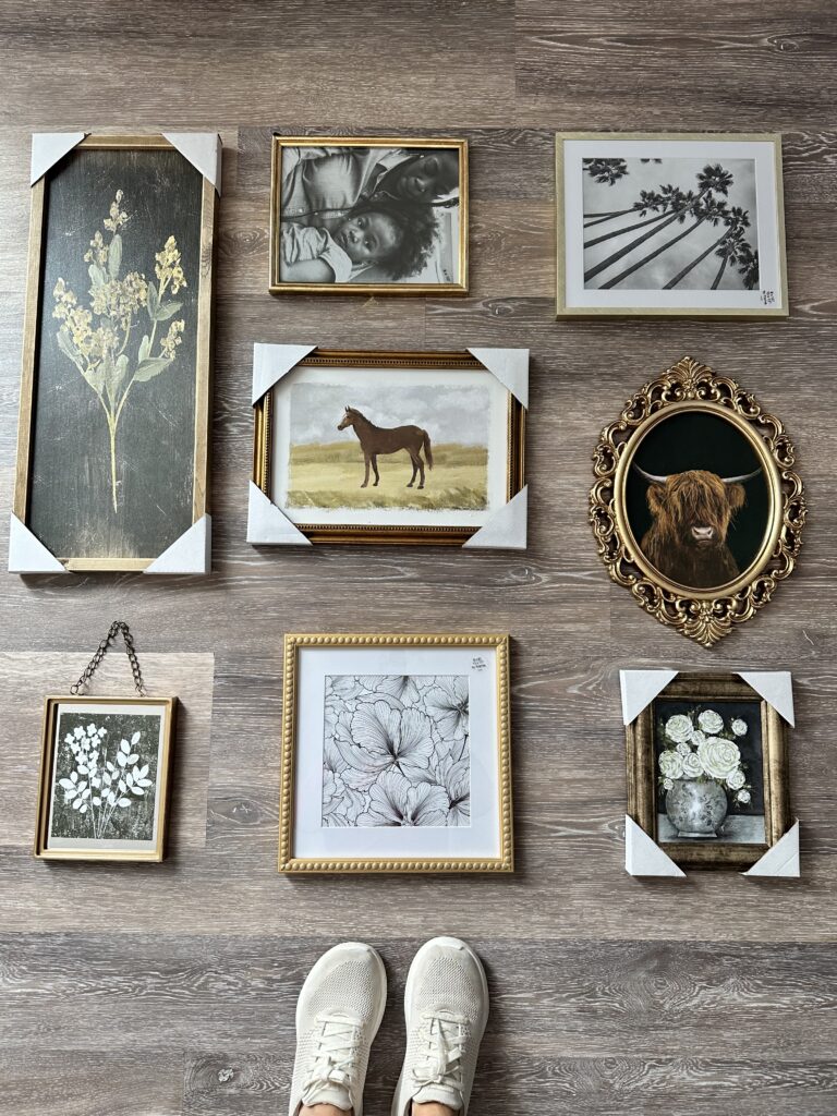 gallery wall laid out on floor for my moody blue powder room project