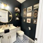 "After" photo of moody blue bathroom with farmhouse decor and gold accents.
