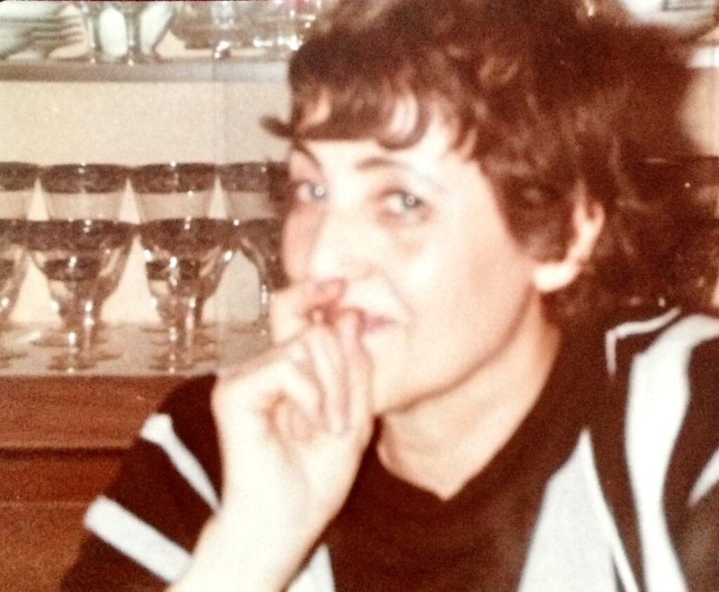 Glamorous Grandma looking toward camera with chin off to the side and hand curled near her mouth.