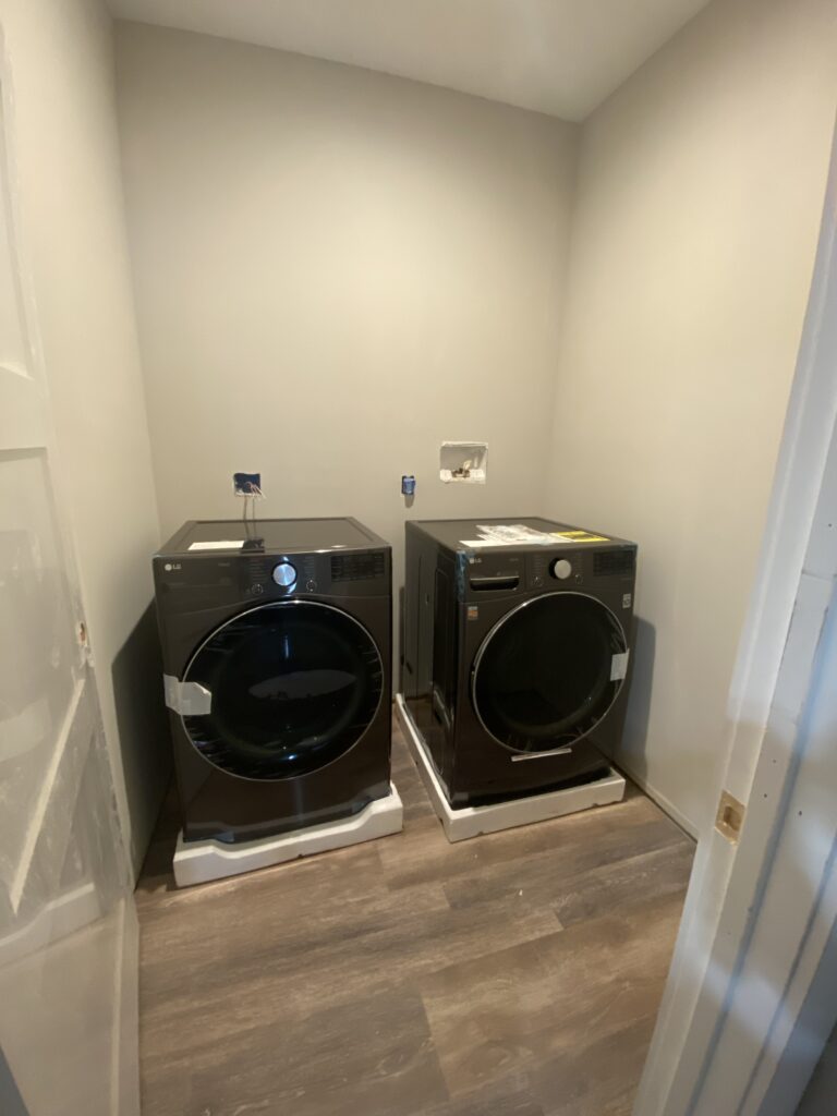 Drab laundry room with no cabinets, countertops or decor