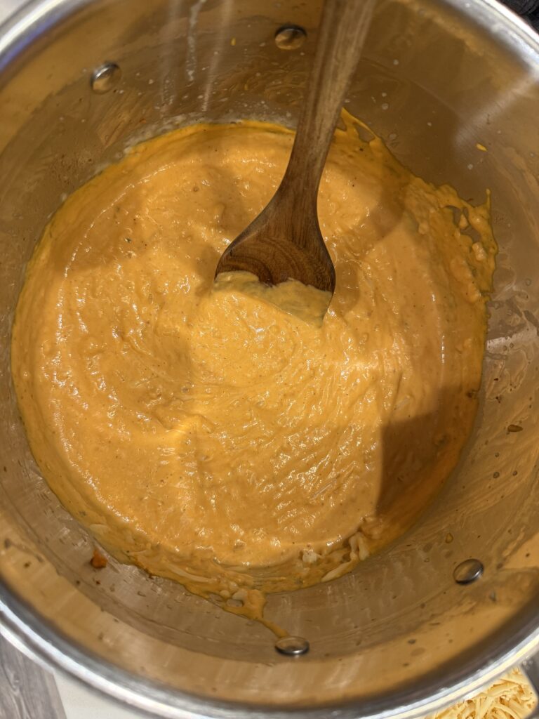 Gorgeous orange pumpkin sauce in stainless steal pot with wooden spoon