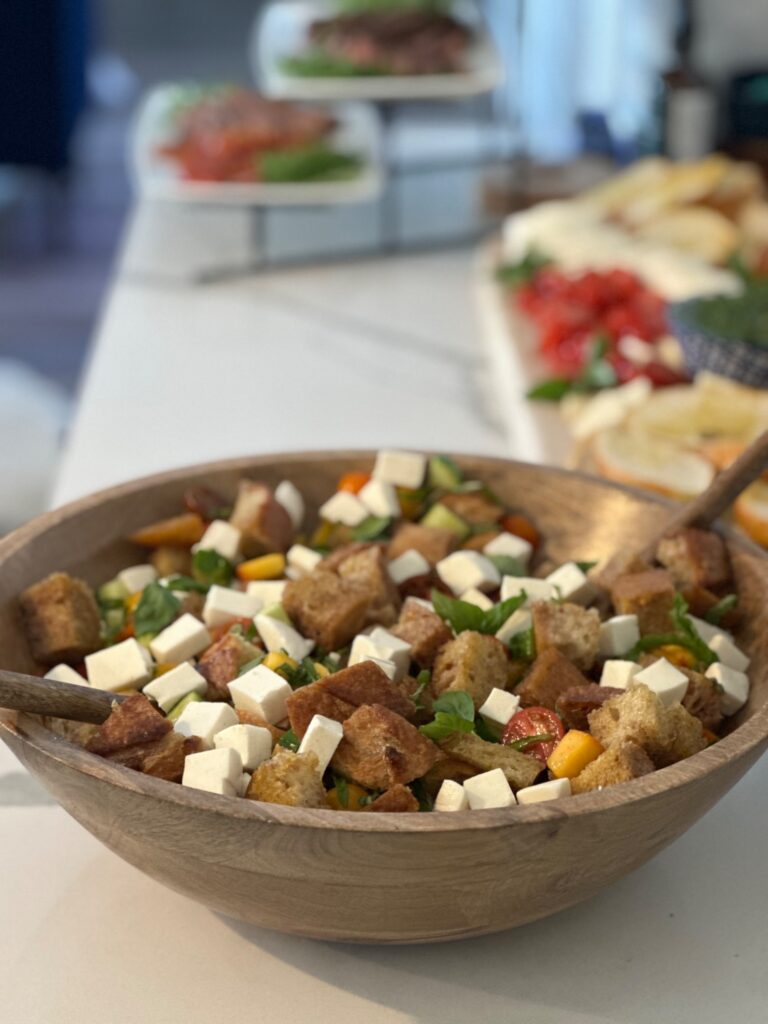 Close-up of peach panzanella salad layered with toasted sourdough bread, mozzarella cubes, cherry tomatoes, cucumbers, fresh basil, and peaches.