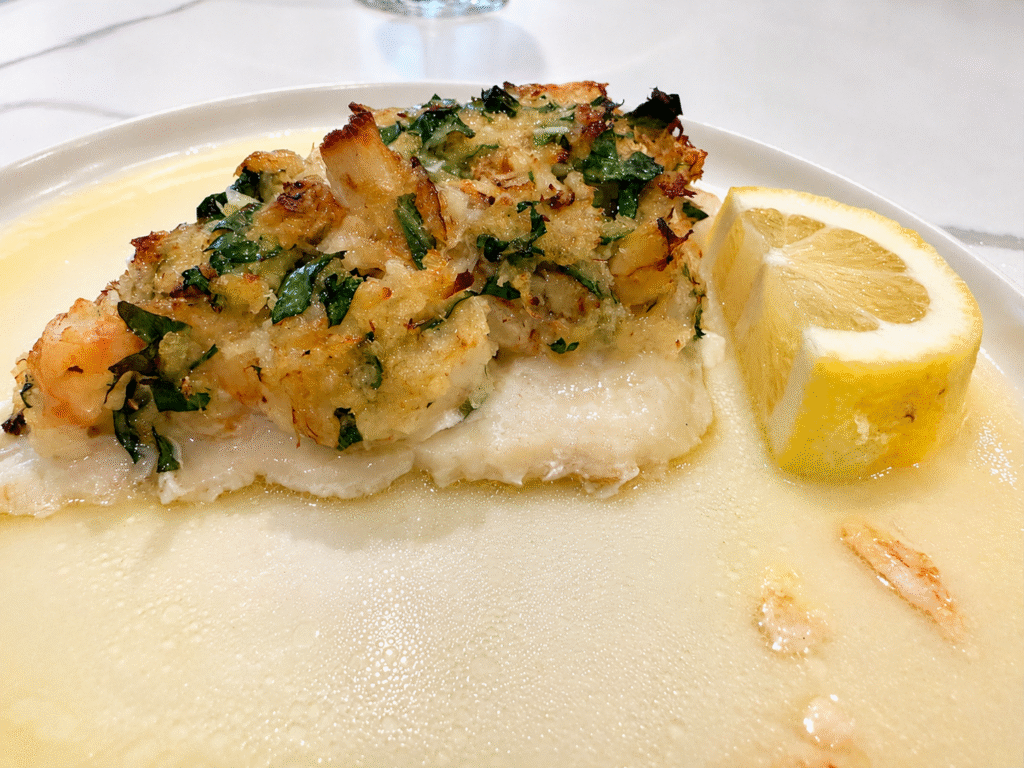 crab & shrimp stuffed monkfish on white plate with lemon slice