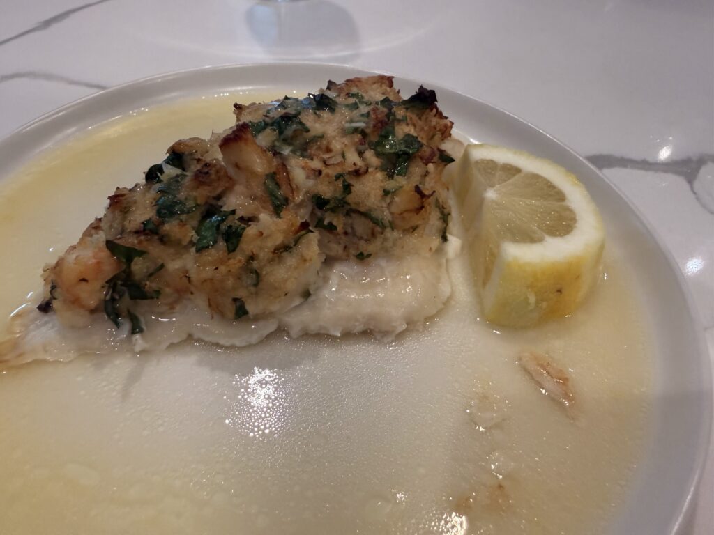 Stuffed monkfish topped with a crab and shrimp stuffing, served in a lemon butter sauce and garnished with fresh parsley and lemon slices.