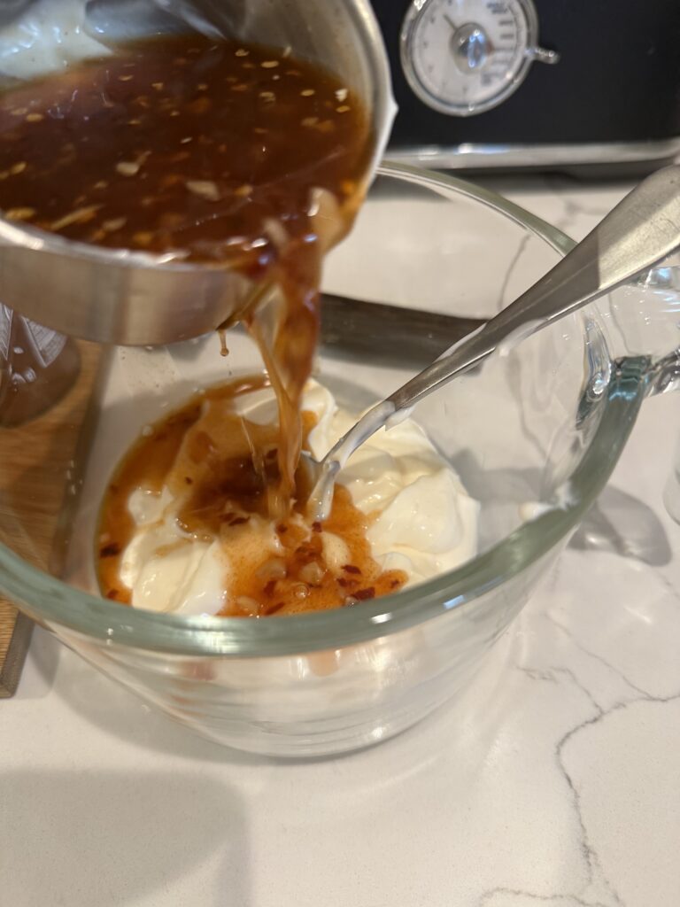 Homemade Thai chili sauce being poured into measured mayo.  