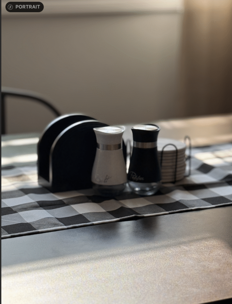 close up of black & white salt & pepper shakers on buffalo pad table runner, in soft morning light