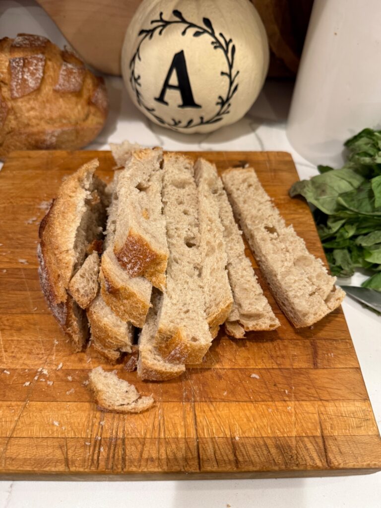 Sliced sourdough bread on a cutting board ready to be toasted for panzanella salad.