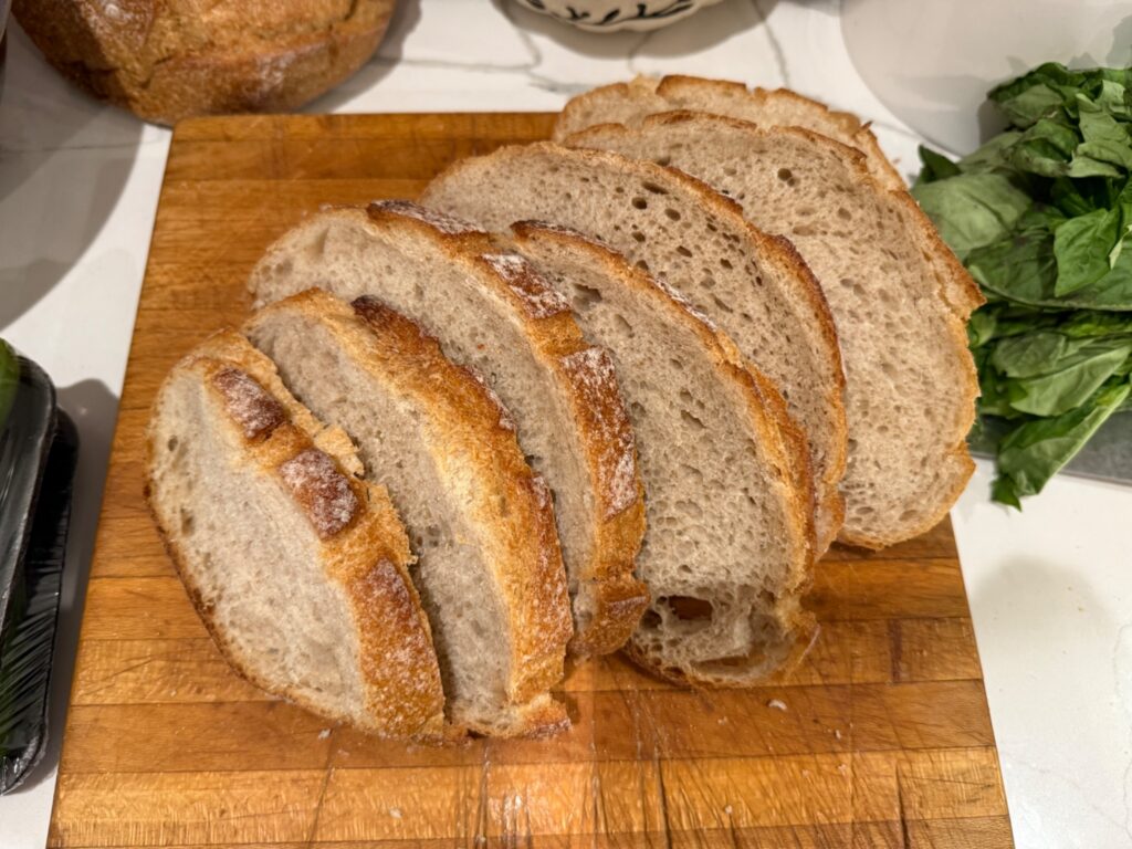 Thick slices of artisan sourdough bread being prepared for toasted panzanella croutons.